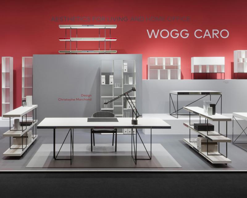 Furniture Fair Cologne 2016 Wogg Caro collection by Christophe Marchand exhibited on cubic platforms in different grey shades in front of a red painted wall 