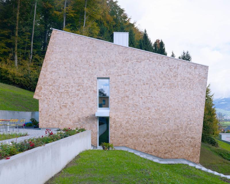 House Tuggen on the edge of the forest with wooden shingles in red cedar