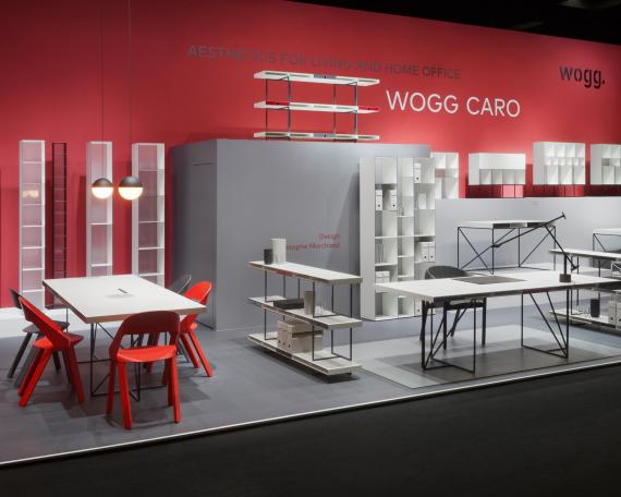 Furniture Fair Cologne 2016 Wogg Caro collection by Christophe Marchand exhibited on cubic platforms in different grey shades in front of a red painted wall 