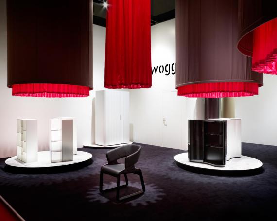 Furniture Fair Milan 2010 exhibition design for Wogg with four hanging fabric cylinders and round display platforms underneath, exhibited furniture from the Amor, Rica and Roya collection