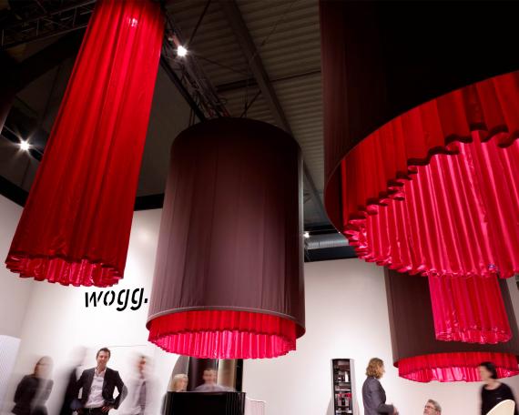 Furniture Fair Milan 2010 exhibition design for Wogg with four hanging fabric cylinders and round display platforms underneath, exhibited furniture from the Amor, Rica and Roya collection