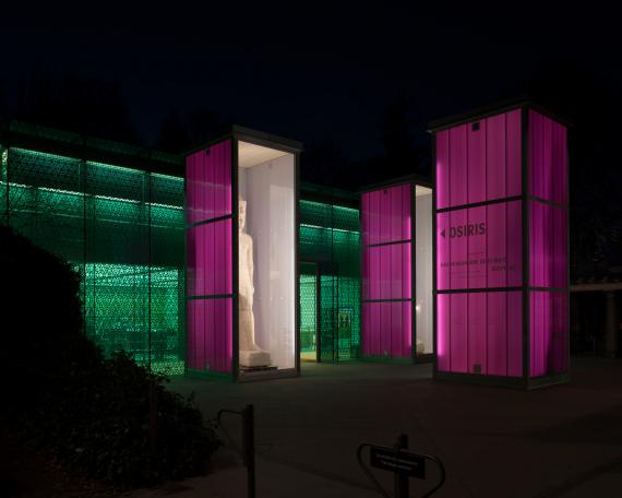 Osiris Ausstellung Museum Rietberg drei Einhausungen in feuerverzinktem Stahl und Polycarbonatplatten in viola Farbton Kolossalstatue König wie Laternen leuchtend bei Nacht