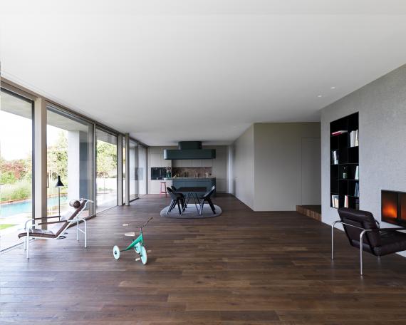 Wohnzimmer mit Betonkern aus sandgestrahltem Beton, Wandverkleidung und Kücheninsel mit Arzo Natursteinabdeckung von Schmitt Natursteinwerk