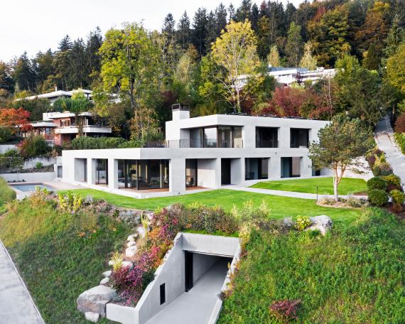 Overall view with garage driveway, garden and pool by Woodtli Schwimmbadtechnik