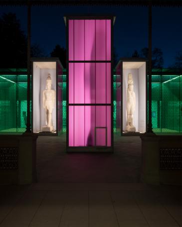 Osiris exhibition Museum Rietberg Three enclosures in hot-dip galvanised steel and polycarbonate panels in violet, shining like lanterns at night in front of the emerald building