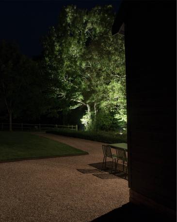 Conversion of barn at Chapel House Farm, Oakwood Hill View into the garden with illuminated oak trees and path