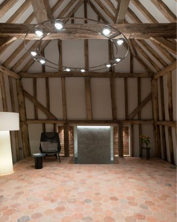 Conversion of barn at Chapel House Farm, Oakwood Hill, Surrey Interior with half-timbered frame and floor with hexagonal terracotta tiles and view toward the stairway in front of Mutina Mews Fog stoneware