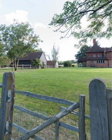 Umbau Scheune Chapel house farm in Oakwoodhill Surrey Scheune mit Holzstülpschalung vorvergraut und Haupthaus mit Tonschindeln und markanten Kaminen 