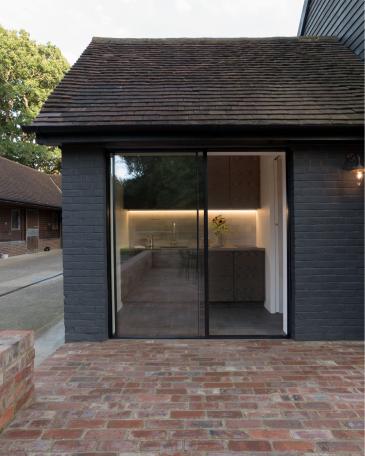 Conversion of barn at Chapel House Farm, Oakwood Hill, Surrey View through the Sky-Frame window into the kitchen of smoked oak and with stone floor 