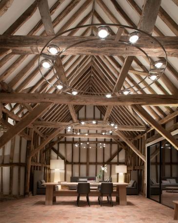 Conversion of barn at Chapel House Farm, Oakwood Hill, Surrey Long oak table from E15 on hexagonal terracotta tiles in front of restored half-timbered frame and Ocular chandelier from Licht im Raum