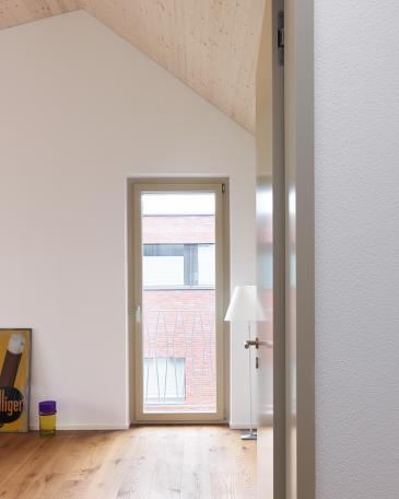 House Wangen_13_Children’s bedroom with wood-panelled gable roof and view of the clinker brick house