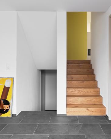 House Wangen_6_Entrance hall with slate floor and parquet staircase leading up to living space level