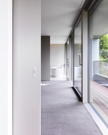 Enfilade Schlafzimmer Richtung Elternbad mit freistehender Badewanne von Heosch vor Wand mit Feinsteinzeugplatten von Winckelmans in super blanc