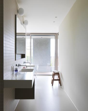 Waschtischmöbel mit Hi-Macs Abdeckung im Elternbad an geplättelter Wand mit Feinsteinzeugplatten von Winckelmans in super blanc