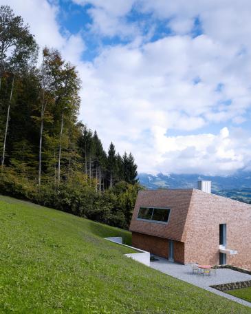 House Tuggen on the edge of the forest with wooden shingles in red cedar and atelier window