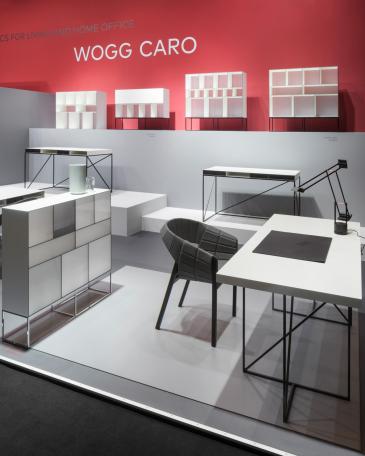 Furniture Fair Cologne 2016 Wogg Caro collection by Christophe Marchand exhibited on cubic platforms in different grey shades in front of a red painted wall 