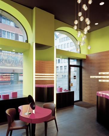 Müller Optik optician store showroom with consulting tables in pink and big backlighted mirror